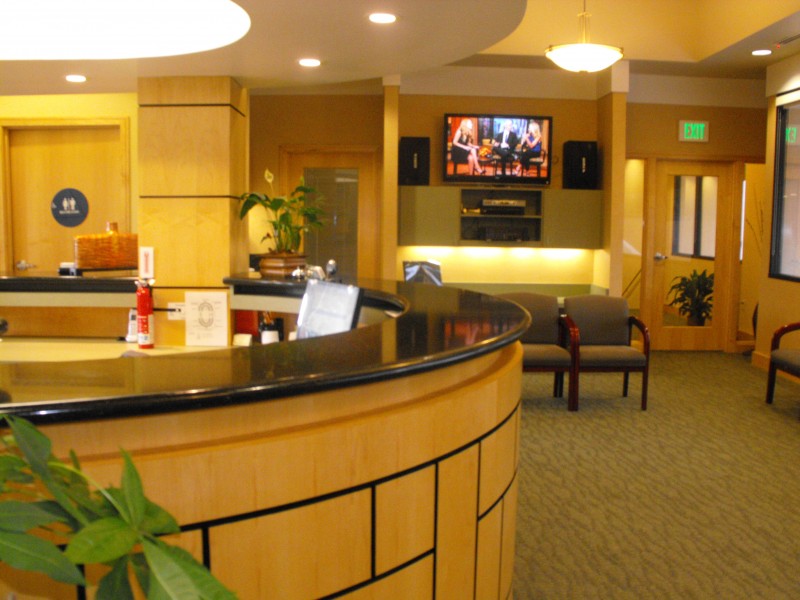 A hotel lobby with a reception desk, seating area, and a mounted television displaying an image.