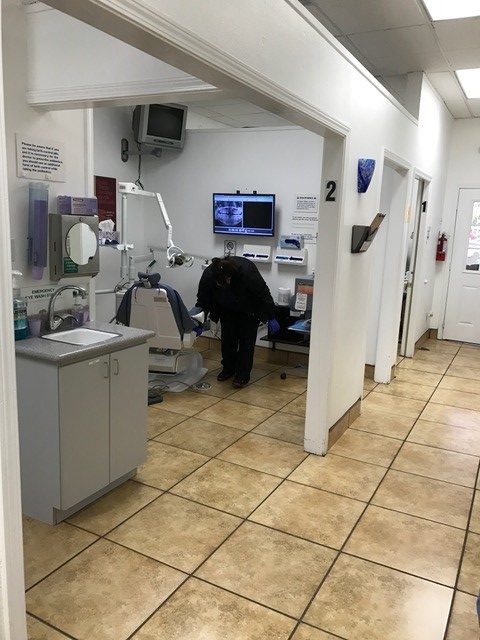 Dental clinic interior with equipment and a person standing near the dentist's chair.