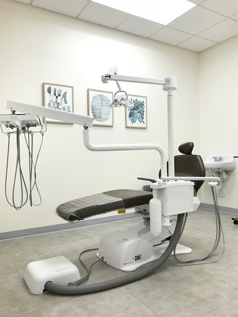 A dental clinic with black dental chair and three pictures on the wall