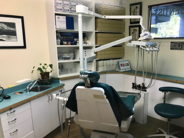 A dental clinic with green dental chair, a green stool, and a green sink