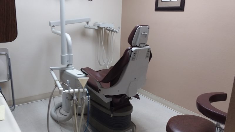 A dental clinic with dark brown-colored dental chair and mauve -colored walls