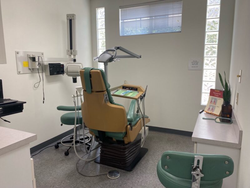 A dentist 's office with an old chair and desk.
