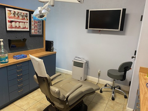A dental clinic with beige-colored dental chair and blue drawers