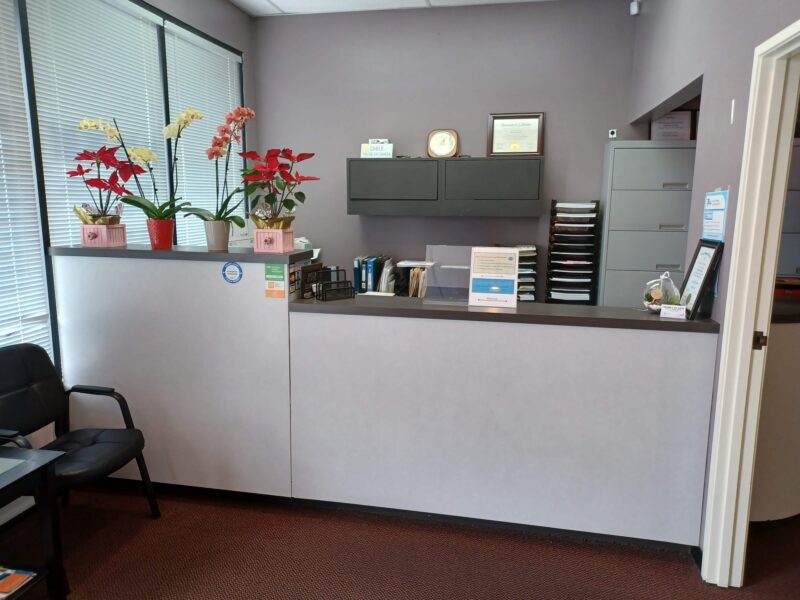 A dental clinic counter with four flower vases on the counter