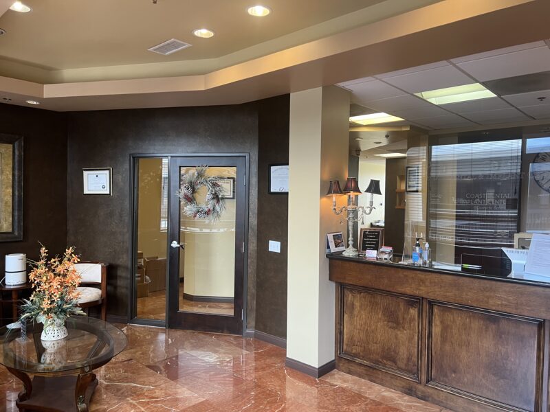 A clinic lobby with classic-designed interior, a brown counter with three-headed lights and brown door