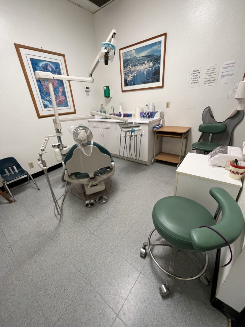 A dental clinic with green chairs and two huge paintings